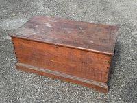 Full view of rectangular pine wooden box showing top and front panel with a dark worn finish and decorative base molding.