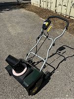 Side angle view of Yardworks electric snow blower showing entire unit, including handle, wheels, chute, and control mechanism.