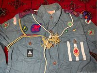 Front view of uniform shirt with badges, epaulet, cord and neckerchief displayed