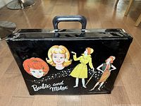 Exterior of black vinyl carrying case with handle and 'Barbie and Midge' printed graphics