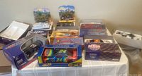 Lot of 10 boxed model race cars displayed on table showing brands and packaging.