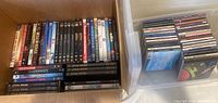 Photo showing a collection of DVDs including Star Wars series, Harry Potter series, Moulin Rouge, The Matrix, and others, along with plastic bin containing CDs.