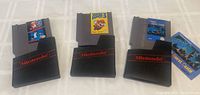 Three Nintendo NES video game cartridges each partially inserted into black Nintendo sleeves, showing front labels.