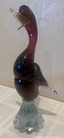 Murano glass duck sculpture side view showing burgundy to maroon gradient with clear glass wings and fluted base.