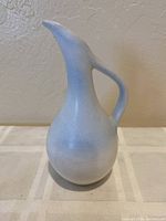 Full side view of Van Briggle pitcher showing the unique pouring spout, curved handle and iridescent blue surface texture.