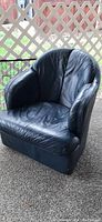 Front view of blue leather swivel tub chair showing seat cushion, rounded arms, and curved backrest with leather upholstery.