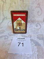 Front view of Marlboro wooden cigarette case showing logo and stained signage.