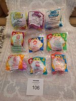 Photo of nine different Muppets toys from McDonald's promotional set, in original sealed packages displayed on fabric surface with lot tag.