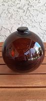 Full front view of the amber-brown glass fish float showing spherical shape and surface reflections.