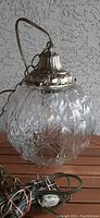 Close-up of retro bubble glass swag lamp showing the clear glass globe with textured bubble design and silver-toned embossed metal top with hanging arm.