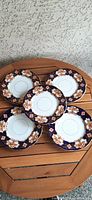 Five Royal Albert Heirloom salad/dessert plates arranged on wooden surface, showing full set and detail of pattern.