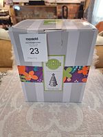 Box with Scentsy branding and product name Trim The Tree with decoration band around.
