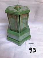 Front view of closed hexagonal green carousel music box showing decorative panel details.