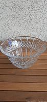 Clear Waterford crystal bowl from three-quarter side angle showing cut crystal design and scalloped edge rim on a wooden surface.