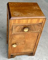 Front and side view of the night table showing walnut wood grain, brass knobs, and surface wear on top.