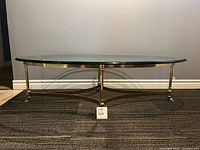 Front view of the table showing elliptical glass top and brass base