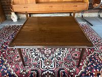 Top view of midcentury modern walnut coffee table showing square surface with raised edges and tapered legs.