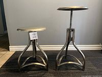 Pair of two metal stools with screw height adjustment mechanism, shown from front