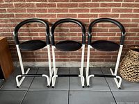 Three stools front view against brick wall.