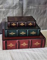 Three faux book boxes stacked showing spines with gold motifs