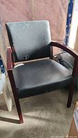 Front angled view of black faux leather armchair