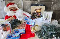 Overview of Christmas decor items including lights, Santa wall hanging, stocking, faux snow, boxed figure, boxed snowman light, jingle bells