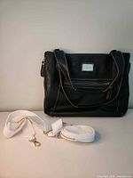 Front view of black tote shoulder bag with white strap and coin purse displayed