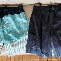 Both pairs of swim trunks side by side on sofa, showing overall appearance and colors