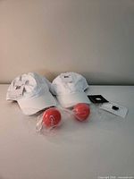 Lot overview showing 2 Nike caps, 2 Apple pins, 2 red keychains