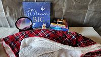 Group shot showing canvas art, sand art, eyeglass holder, plaid throw, and six books