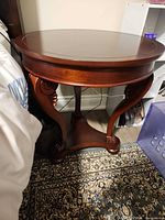 Full view of round mahogany side table beside bed
