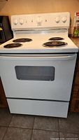 Front view of white Moffat electric range showing four coil burners, control panel, oven door and storage drawer