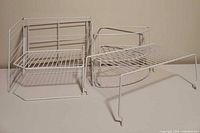 All four white wire shelves grouped: two quarter-circle corner units, two rectangular stacking units