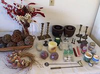 Full lot showing candlestick holders, dried floral bouquets, wooden bowls, decorative spheres, jar candles, wax pillar candle, and candle accessories.