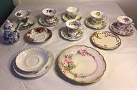 Full overview of 6 floral bone china cups and saucers with 5 matching dessert plates placed on a flat cloth surface.