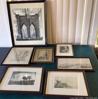 Overview of all seven framed black and white artworks laid out on a table showing various sizes and themes.