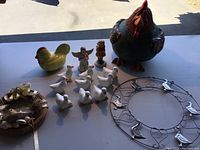 Overview of lot items on table showing chicken cookie jar, small bird figurines, angel figurines, and wire wreath with bird decorations.