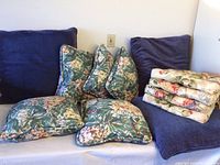 Set of floral seat cushions, floral back pillows, and large blue pillows arranged on a couch.
