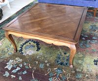 Square wood coffee table showing the criss cross inlay pattern on the tabletop and cabriole legs.