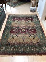 Full view of the rectangular area rug laid out on wood floor near furniture, showing entire pattern and fringe edges.
