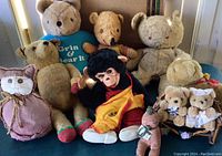 Group showing assortment of vintage teddy bears and stuffed animals, some with clothing and signs of wear, arrangement to capture all toys.