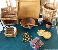 Full display of wooden and woven kitchenware including cutting board, bowls, baskets, napkin rings, coasters, mugs and boxed candles.