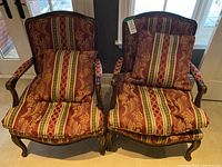Two matching vintage occasional chairs with carved wood frames and red, gold, green striped upholstery