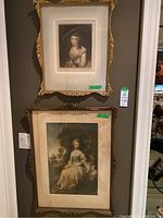 Overview of both framed prints hanging on wall showing relative sizes and frame condition