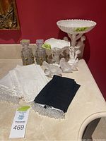 Full group view of bathroom decor including angels with crystal containers, ceramic bowls, bird figurines, and towels on a white counter against red wall.