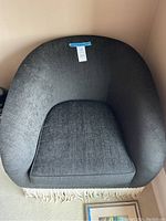 Front view of black barrel arm chair with white tassel fringe