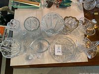 Top-down group shot of eleven pieces: vases, bowls, platter, compote, creamer, lidded box, salt shaker