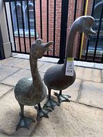 Front view of two metal duck sculptures with stickers