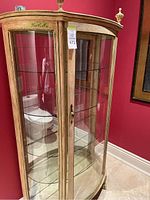 Front view of painted wood frame curio cabinet with curved glass doors, 4 interior glass shelves, decorative finials and claw feet