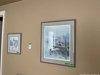 Two matte‐framed prints hung side by side on a tan wall
